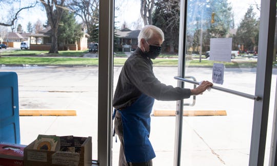 Doug Beavers, co-owner of Fort Collins' only family-owned full-service grocery store Beavers Market, sanitizes the door handle to the store in Fort Collins, Colo. on Monday, April 20, 2020.