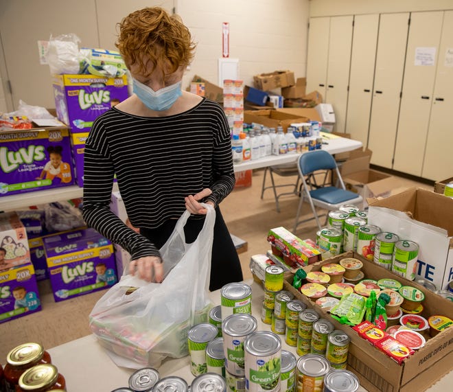 Evren Elliott, a volunteer at No Questions Asked, a food pantry started by Satch Cole, bags up items for a family, Indianapolis, Thursday, May 21, 2020. The pantry, which has operated out of several locations, is currently at The Church Within, at 1125 Spruce Street, and offers food and diapers, as well as cleaning supplies, tampons, condoms, and other personal and household items through a drive up service three days a week. 