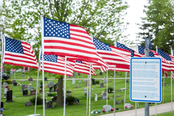 A sign at Oak Hill Cemetery lists policies about decorations on graves as American flags line the road prior to Memorial Day during the novel coronavirus, COVID-19, pandemic, Friday, May 22, 2020, in Coralville, Iowa.