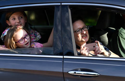 Beth Laurence holds her phone, waiting to get a picture of teachers lined up outside of Austin Elementary School Tuesday May 19, 2020. Behind her, Emma and Abby Gragg look for their mother Betsy, the school art teacher, while Beth's husband David drives.