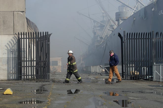 Fire officials walk near a warehouse after a fire broke out before dawn at Pier 45 at Fisherman's Wharf in San Francisco on May 23, 2020.