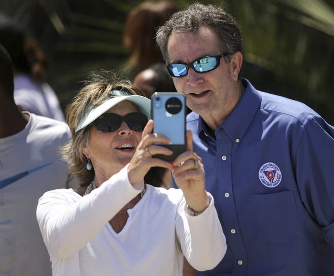 In this Saturday, May 23, 2020, photo, Gov. Ralph Northam and Tori Bloxom, of Onancock, Va., take a selfie as the governor visits the Oceanfront in Virginia Beach, Va., to see for himself how crowded the beach was. Northam has repeatedly urged Virginia residents to cover their faces in public during the COVID-19 pandemic, but the Democrat didn’t heed his own plea when he posed mask-less for photographs alongside residents during the weekend beach visit. A spokeswoman for the governor’s office said on Sunday that Northam should have brought a face mask with him during his visit on Saturday to the Virginia Beach Oceanfront.