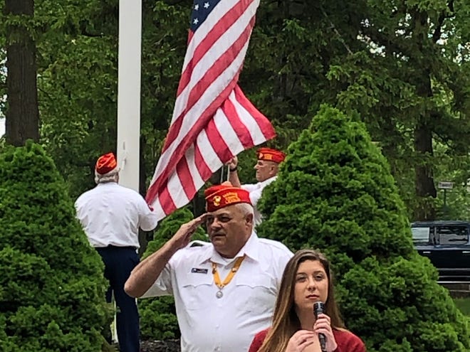 Vineland High School senior Alexandra Brodzik performs the National Anthem while Edwin Alicea, the United Veterans Council President, salutes during a Memorial Day observance in Landis Park in Vineland. May 25, 2020