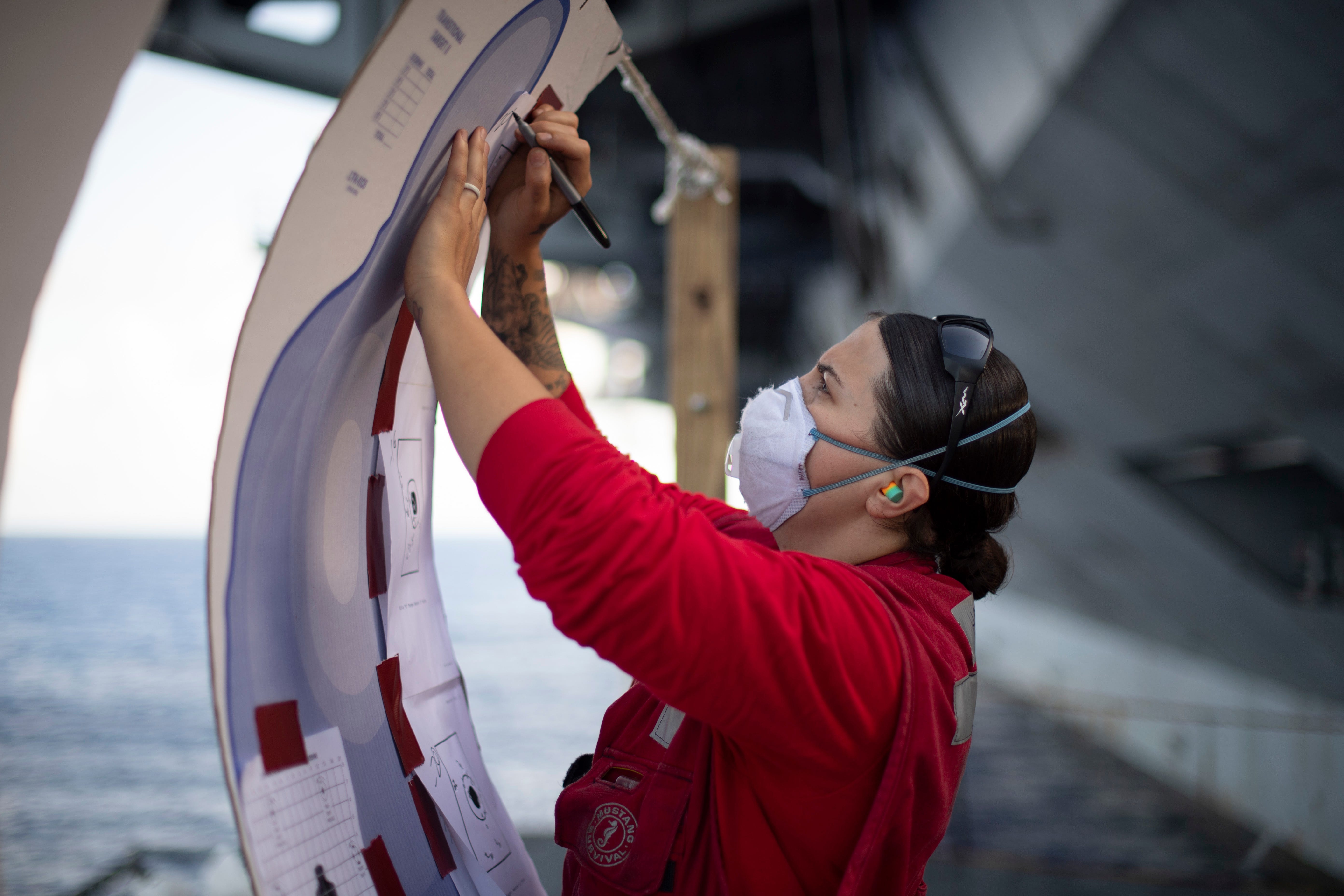 Navy Gunner’s Mate 2nd Class Angela Haley, from Farmington, Minn., checks a target board after a small arms qualification aboard the aircraft carrier USS Theodore Roosevelt Sunday. Following an extended visit to Guam in the midst of the COVID-19 global pandemic, Theodore Roosevelt is underway conducting carrier qualifications.