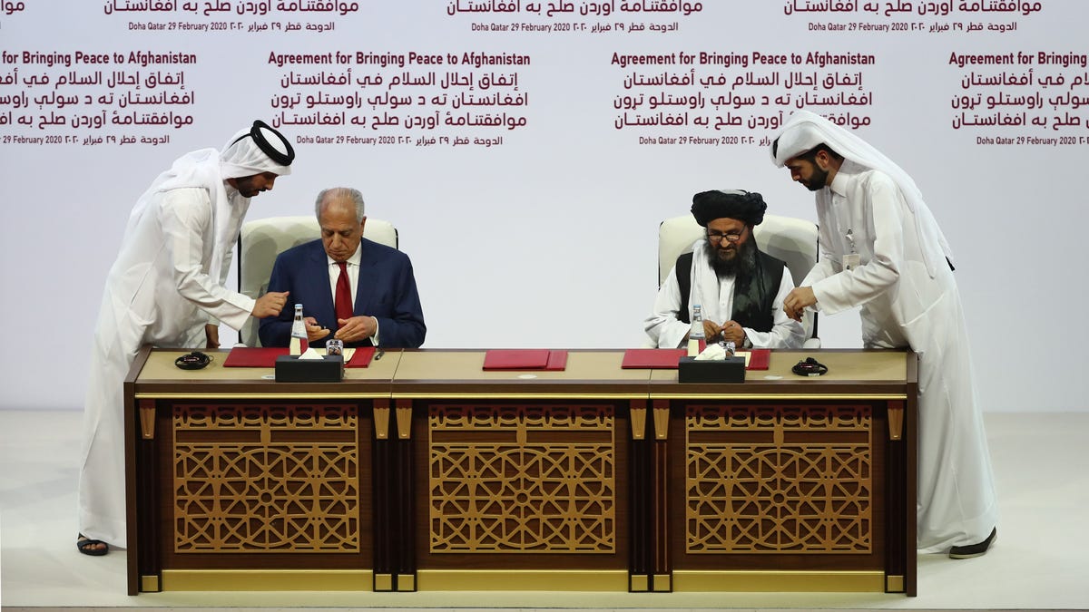 U.S. envoy Zalmay Khalilzad, left, and Taliban co-founder Mullah Abdul Ghani Baradar sign a peace agreement in Doha, Qatar, on February 29, 2020.