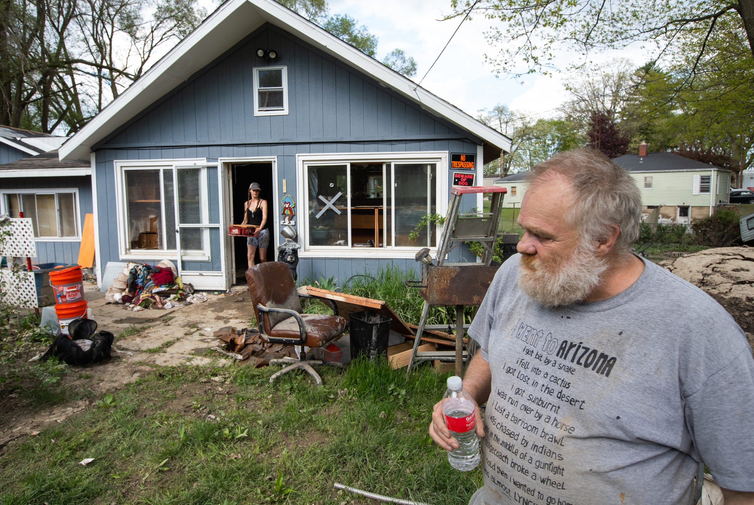 Kenneth Helm walks through his yard in Sanford on Friday, May 22, 2020, as his sister Kim Helm of Standish helps him clear out his home, which was damaged by flood waters three days earlier.