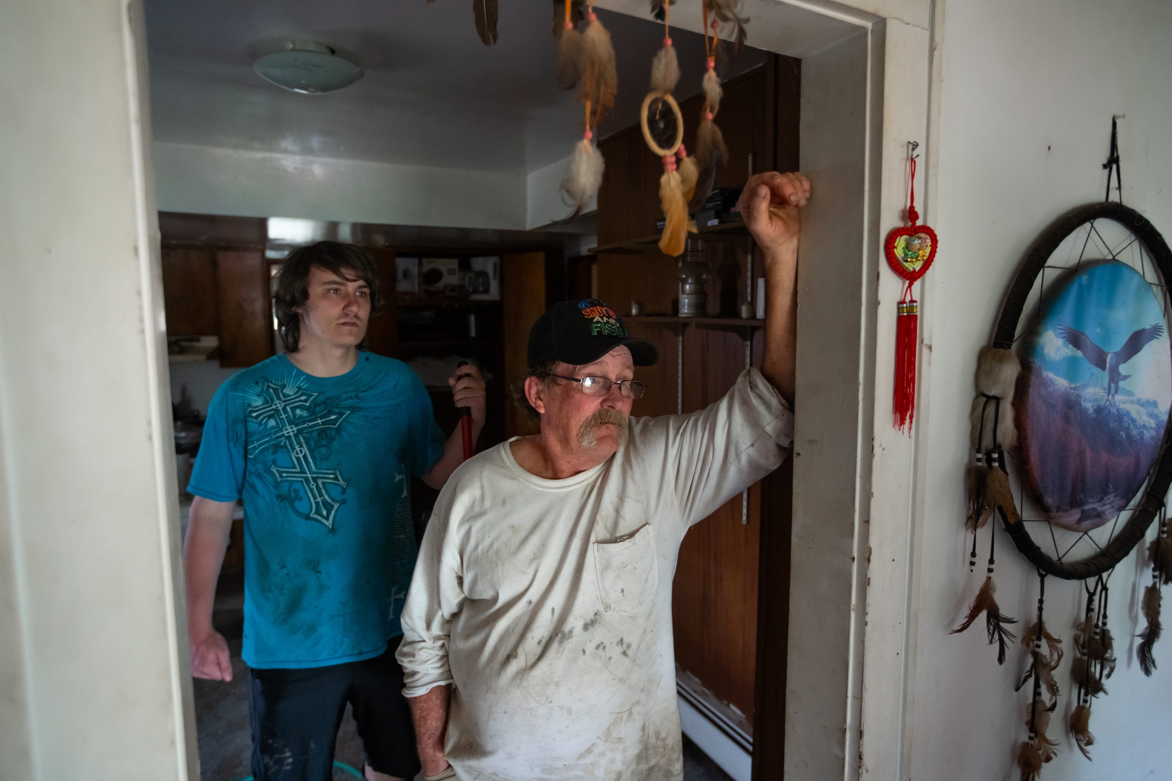 Jim Mcguire stands in the kitchen doorway of his flood-damaged home on Friday, May 22, 2020, as his son Robert Mcguire stands behind him. "It's tearing me up," said Jim. "I ain't broke down yet, though. When it's all done and I personally feel that once I have my home stable to where I can live in it somewhat, that's when I'm gonna break down."