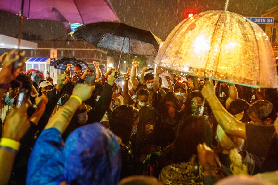 Protesters gather under the rain near the spot where George Floyd died while in custody of the Minneapolis Police.