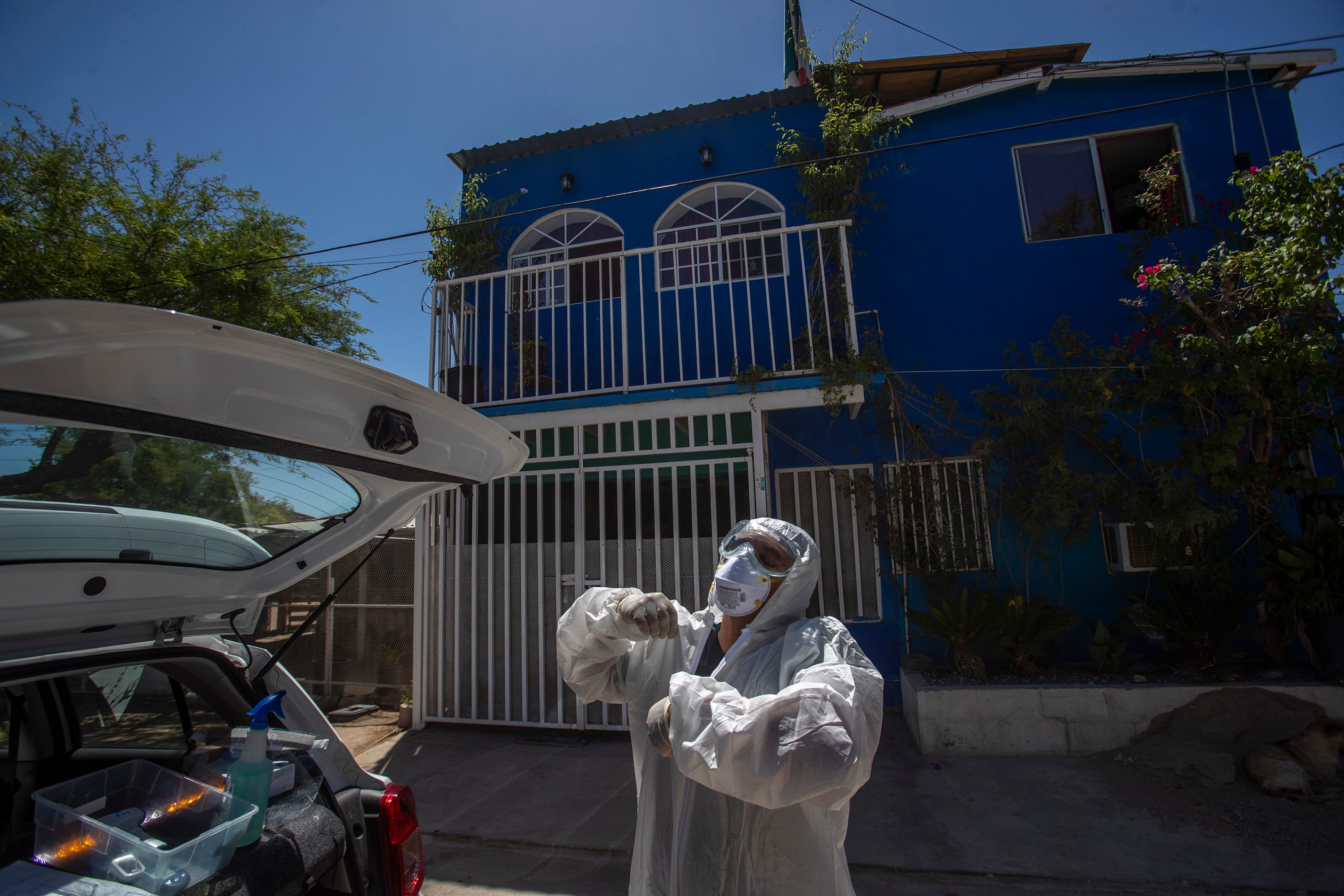 Hector Rivera Lagunas performs the ritual after entering a COVID-19 suspect home of taking off a tyvek suit after being decontaminated at a site.