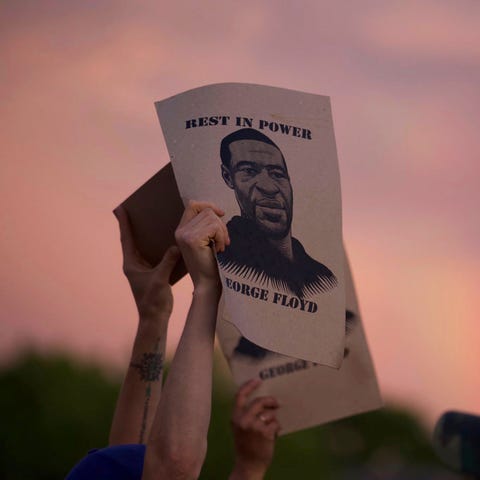 A protester holds a sign with an image of George F