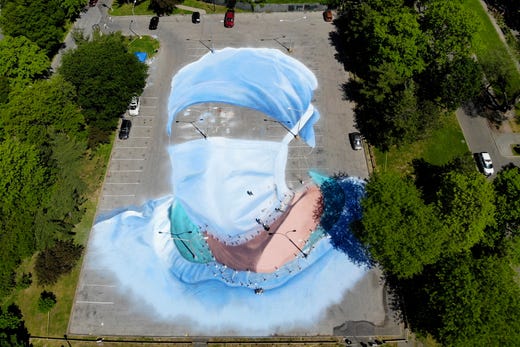 Artist Jorge Rodriguez-Gerada works on a 20,000-square foot mural of a health care worker in a parking lot in Flushing Meadows Corona Park in the Queens borough of New York on May 27, 2020.
