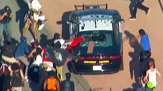 This aerial image provided by KABC-TV shows protesters attacking a California Highway Patrol cruiser during a Black Lives Matter protest on a freeway in downtown Los Angeles on Wednesday.