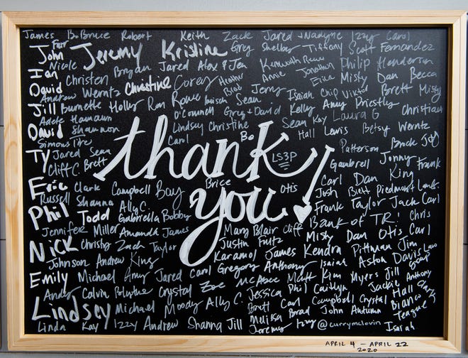 A "Thank You" board where customers can sign their name, hangs on the wall inside Woodside Bistro.