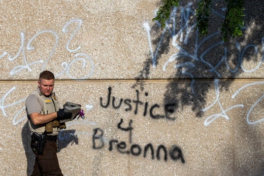 A sheriff's department employee carries evidence used to break windshields during Thursday night's protest regarding recent deaths at the hands of police in Louisville and Minneapolis. May 29, 2020