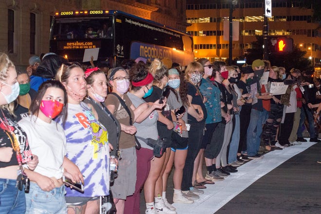 A line of almost all white women formed between police officers and black protesters at Thursday night's rally in downtown Louisville calling for justice in the death of Breonna Taylor.