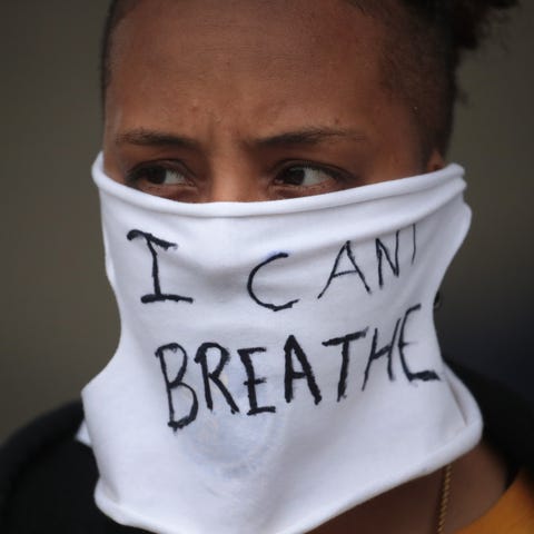 A person wears a mask that reads "I CAN'T BREATHE"