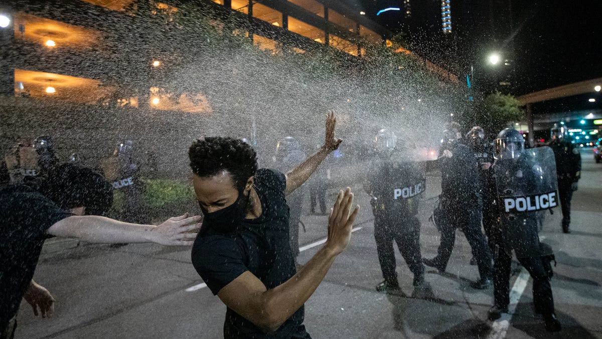 Protesters are sprayed with pepper spray by Detroit police officers in riot gear in downtown after an afternoon march and rally against police brutality extended into the evening and became contentious on Friday, May 29, 2020 in Detroit.