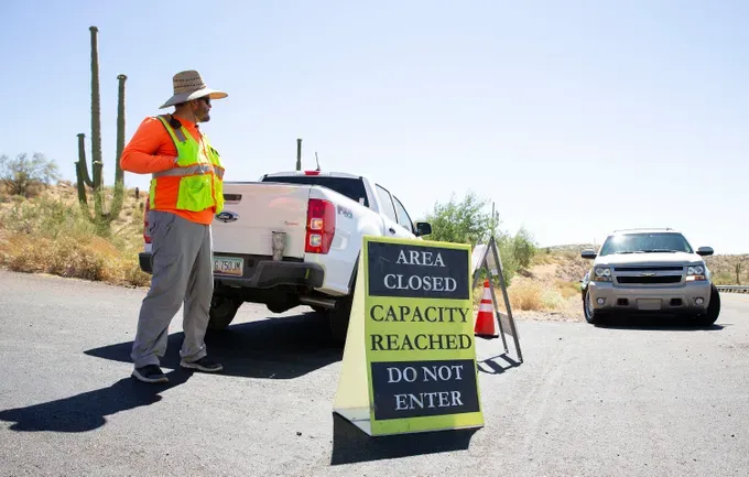 Park supervisor David Jordan guards the entrance to one shoreline campsite after capacity was reached on Memorial Day at Lake Pleasant in Arizona on May 25, 2020.