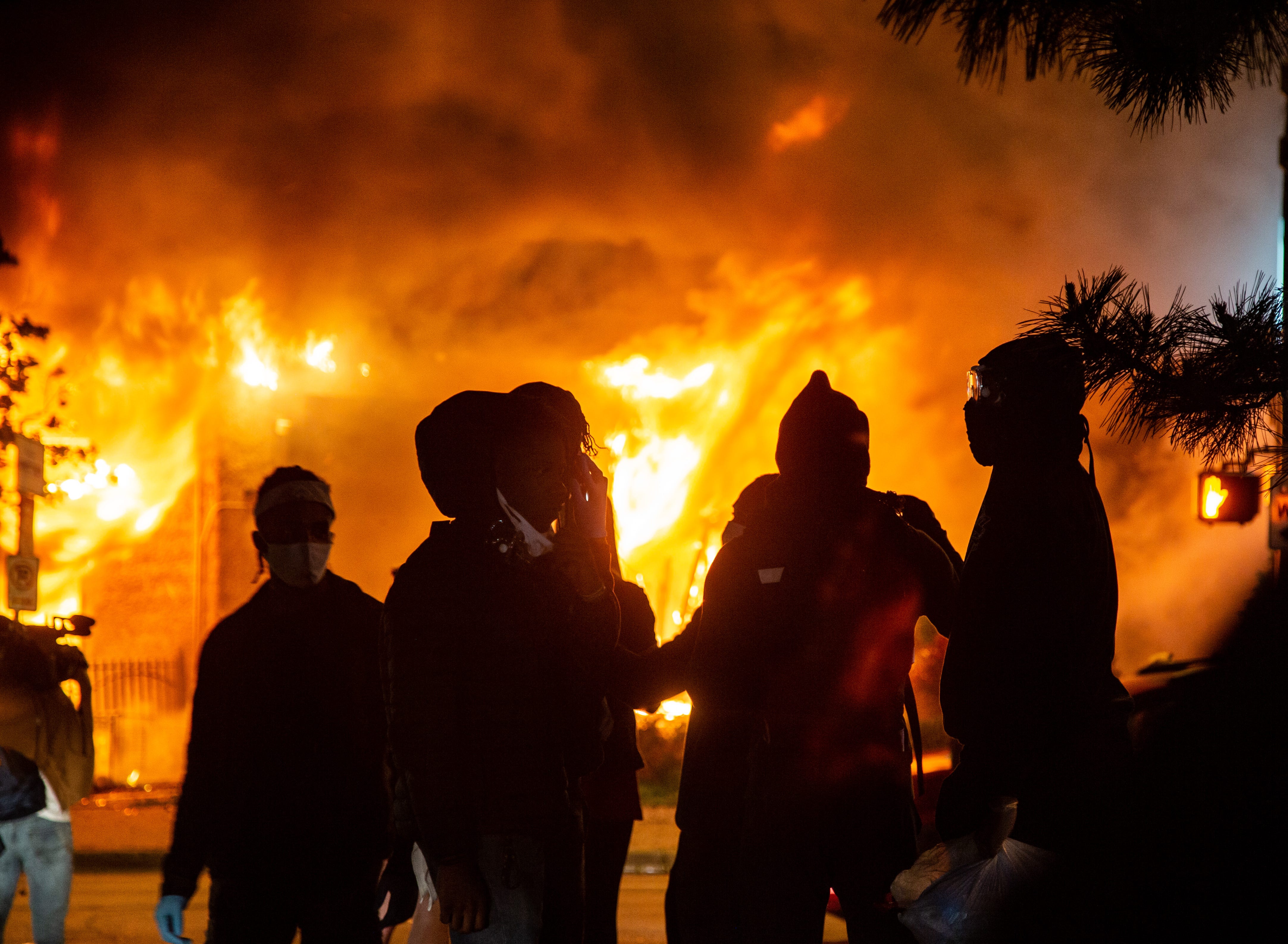 Protestors watch a building burn on Lake St. in Minneapolis Friday, May 29, 2020. Protests continued around the city following the death of George Floyd, a black man who died in police custody. (Via OlyDrop)