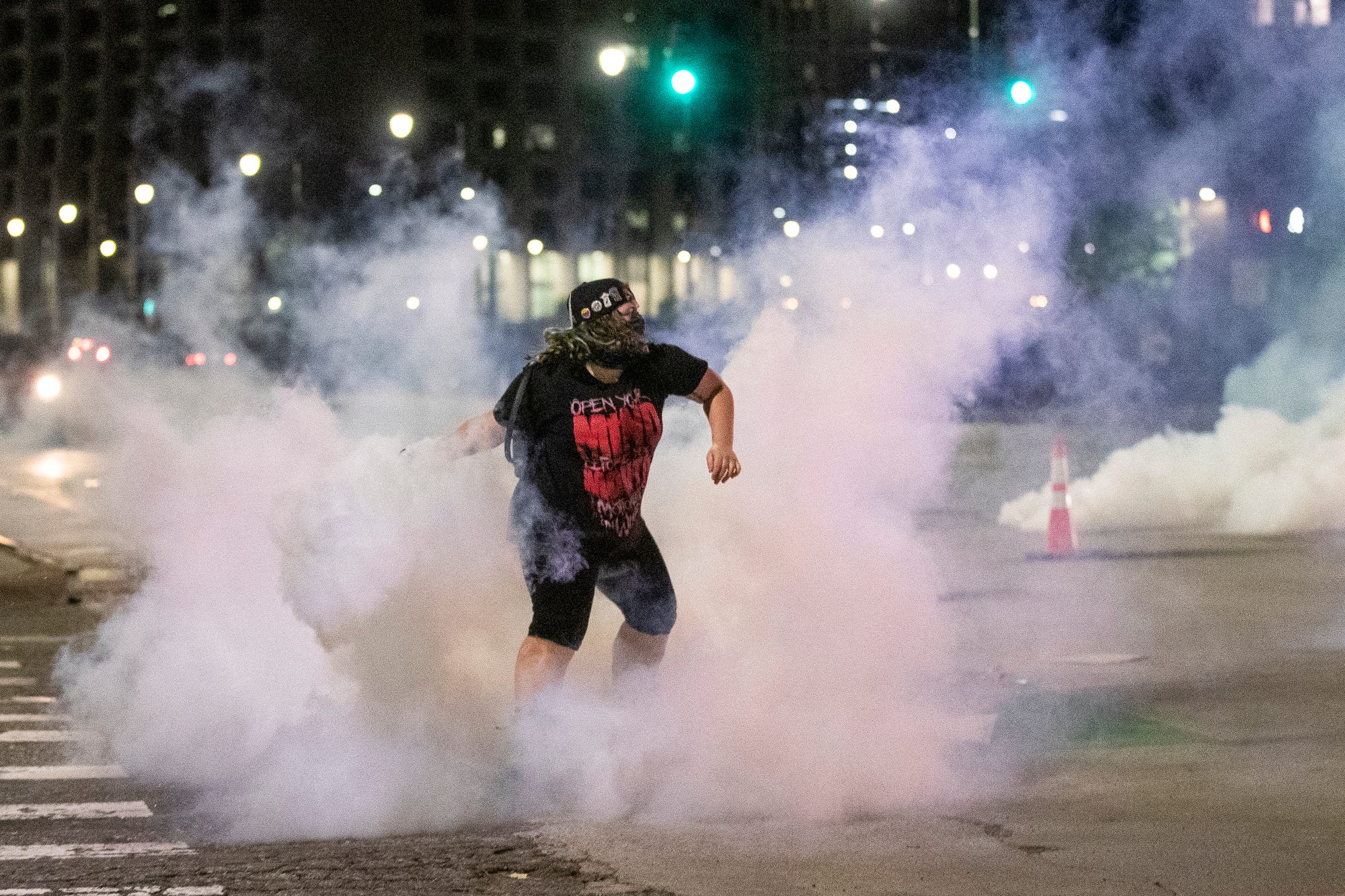 A protester throws tear gas shot by Detroit Police back toward the officers at the corner of Third Avenue and Michigan Avenue in Detroit, Saturday, May 30, 2020.