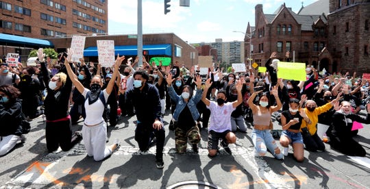 Protestors raise their hands as they kneel in front of the Yonkers police headquarters during a march and rally in Yonkers, N.Y. May 31, 2020 to protest the death of George Floyd in Minneapolis. 