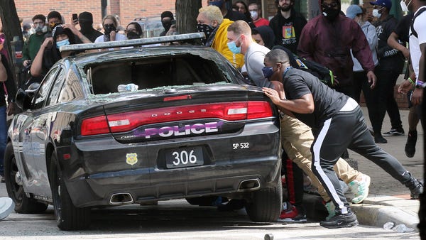 Protesters try to overturn a damaged Cleveland pol