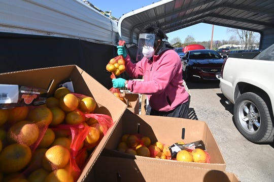 Kay Lewis, water coordinator, grabs bags of oranges for clients at Greater Holy Temple in Flint on Thursday, May 7, 2020. 