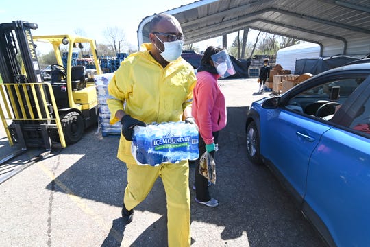Volunteer Cory Anderson carries cases of bottled water for clients at the Greater Holy Temple in Flint on Thursday, May 7, 2020.