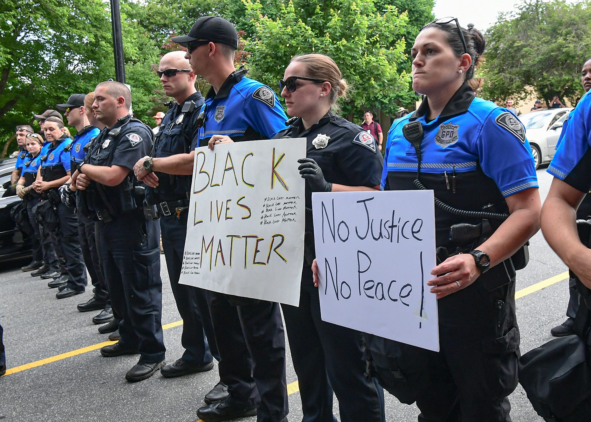 Greenville police S.N. Bowdoin holds a "No Justice No Peace" sign protester Taurice Bussey gave her during a protest remembering George Floyd at Falls Park in Greenville Sunday, May  31, 2020.