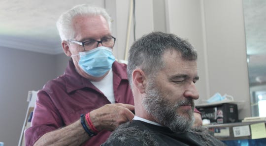 Owosso barber Karl Manke cuts Randy Hamilton's hair on Tuesday, June 2, four days after a court ordered him to cease all operations at his shop.
