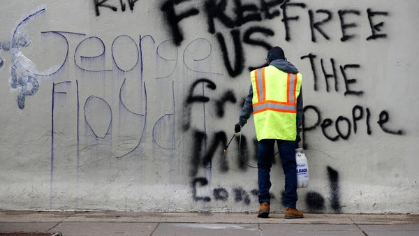 A worker removes graffiti from a building, Tuesday