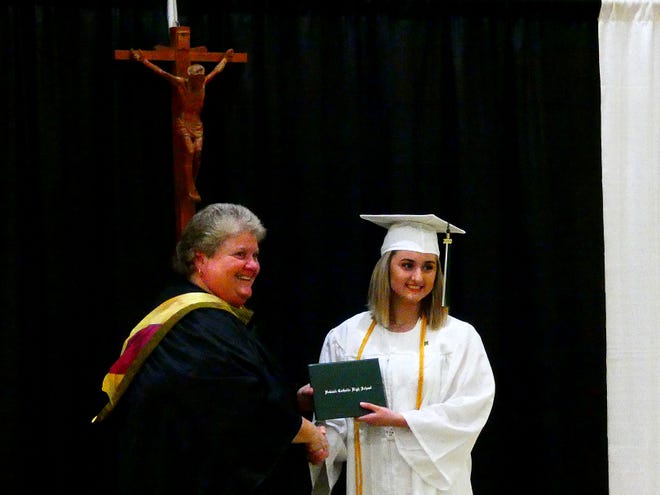 Alexis Miller (right) receives her diploma from Newark Catholic High School principal Beth Hill (left) during the first half of their graduation ceremony on Tuesday, June 2, 2020 at the high school. Students donned their caps and gowns and came through with a small group of family to receive their diplomas.