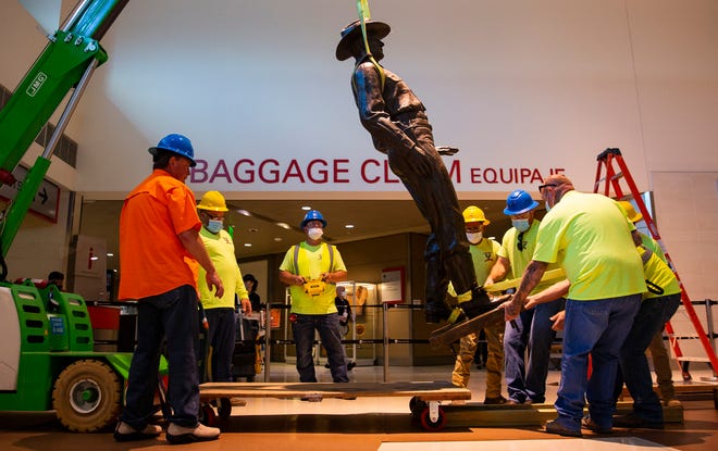 A Phoenix 1 Restoration & Construction crew removes a 12-foot-tall bronze statue of a Texas Ranger, called "One Riot, One Ranger,"  from the main lobby inside Love Field airport on Thursday, June 4, 2020 in Dallas. (Juan Figueroa/ The Dallas Morning News via AP)