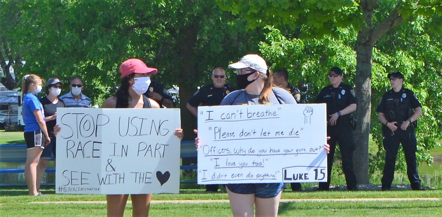 Gabrielle of Green Bay and Mikayla of Oconto Falls, who only gave their first names, hold signs during a protest in Oconto on June. 4. Behind them are Oconto Police officers who were on hand to make sure they demonstrators were not harassed.