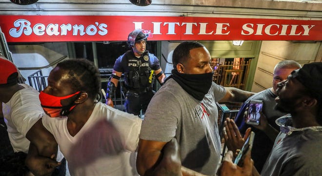 Protesters surround Louisville Metro Police Department officer Galen Hinshaw in front of Bearno's restaurant on Thursday, May 28, 2020 in Louisville, Kentucky. Five strangers, including Julian De La Cruz, Ricky McClellan, (far right) and Darrin Lee Jr. (center, right), linked arms to keep the crowd from getting to Hinshaw.