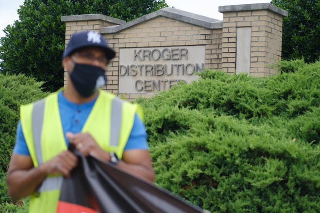 A Kroger employee holds the corner of a banner outside of the food distribution warehouse where he works during a protest, calling for better protections of essential food supply chain workers, Wednesday, Jun. 10, 2020, in Memphis, TN.