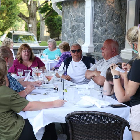 A waitress takes orders as people enjoy outdoor di
