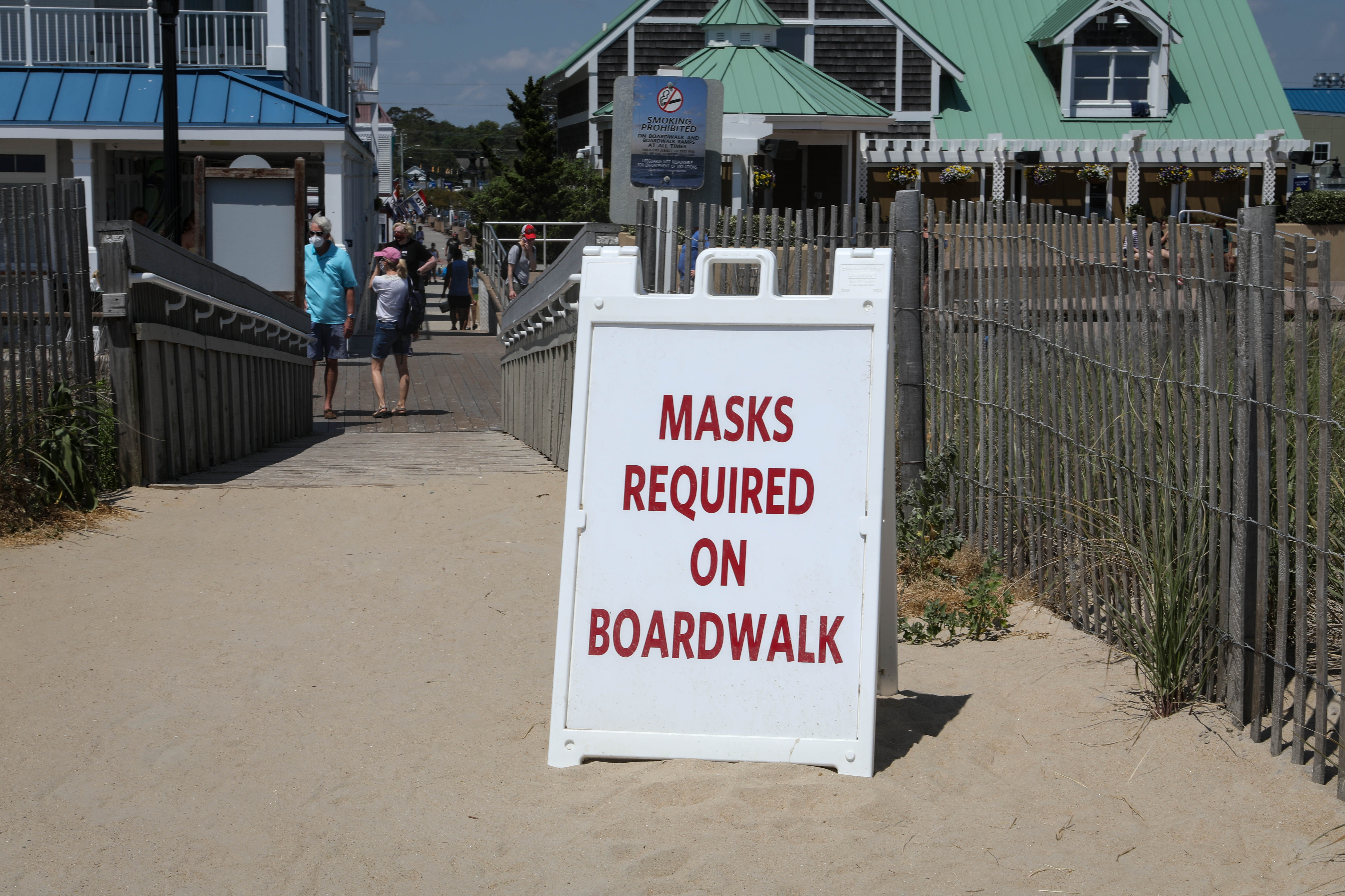 A sign sits on the entryway to a crowded Bethany Beach on a warm breezy Wednesday, June 10. Masks are required on the boardwalk but not the beach.