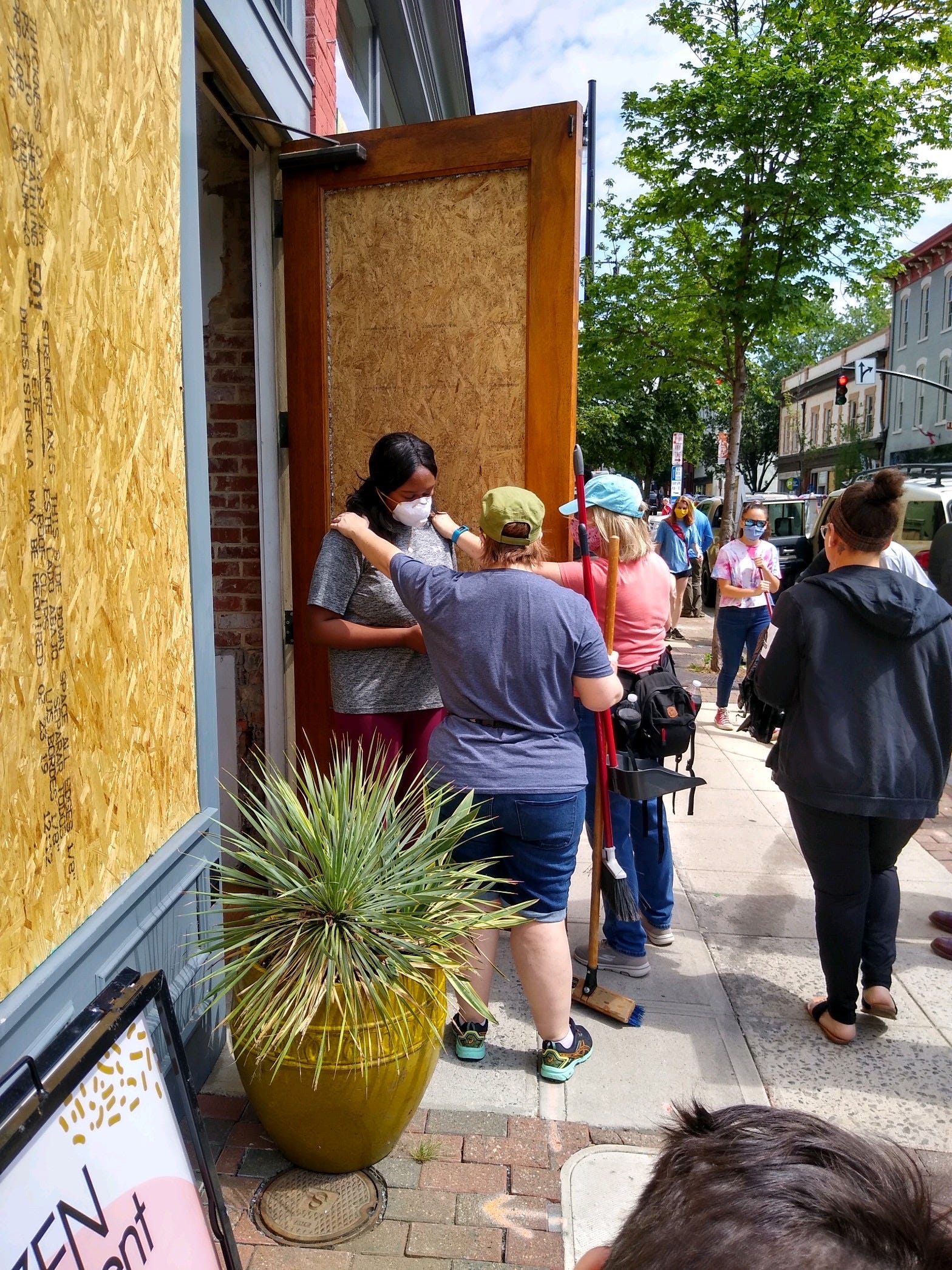 Megan George Cain being comforted by the Raleigh, North Carolina community who came out to help her board up her shop.