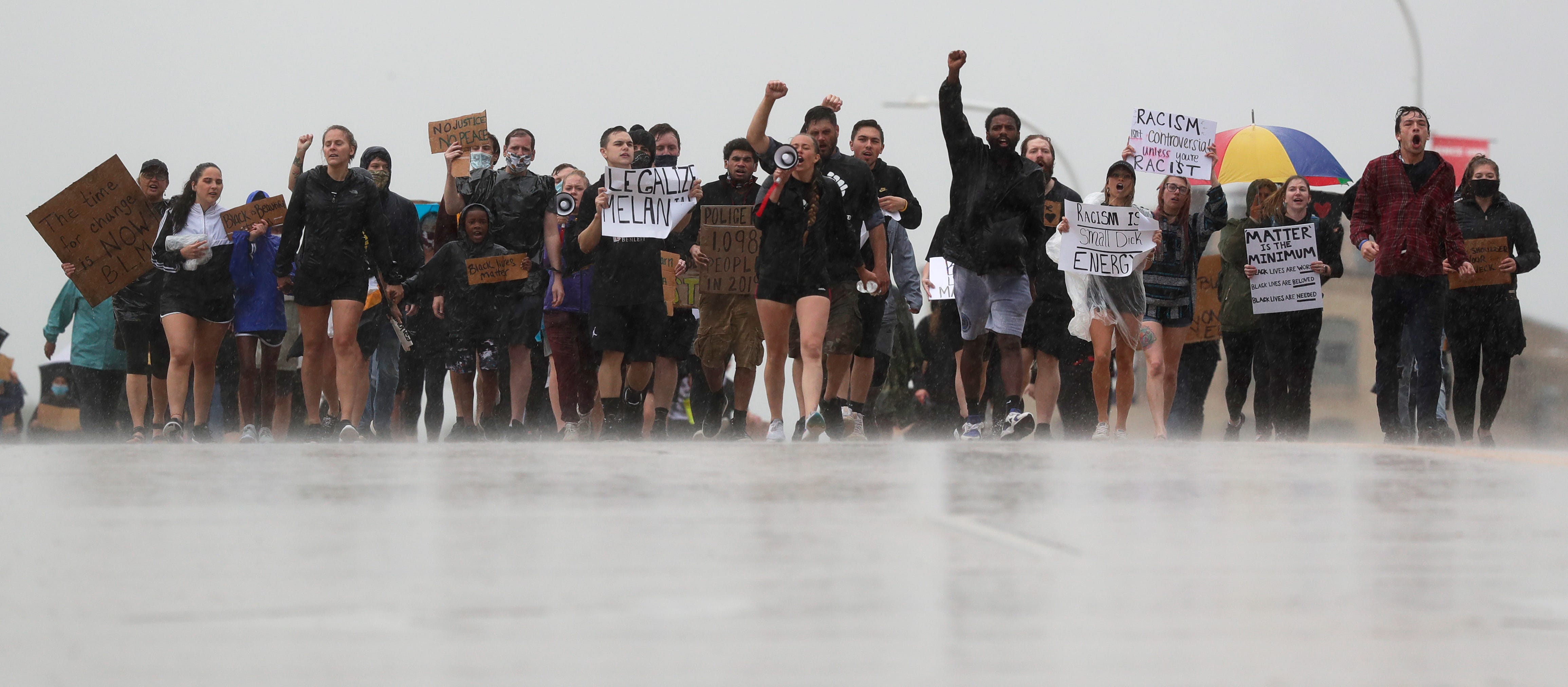 Protesters march across the Claude Allouez Bridge in De Pere to demand an end to police brutality during a rain storm on June 10, 2020.