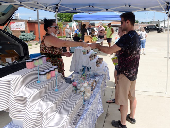 April Lentz, of Thacker Hollow Studios, sells artisan soap to a customer last Saturday at the Zanesville Farmers Market at Adornetto's Select Italian Foods. Lentz is one of numerous local vendors who sells products at the market.