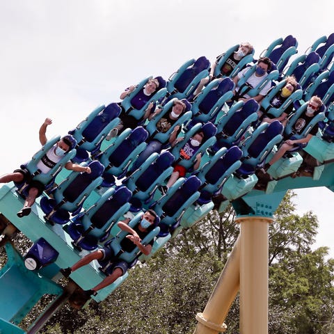 Masked guests ride a roller coaster at SeaWorld Or