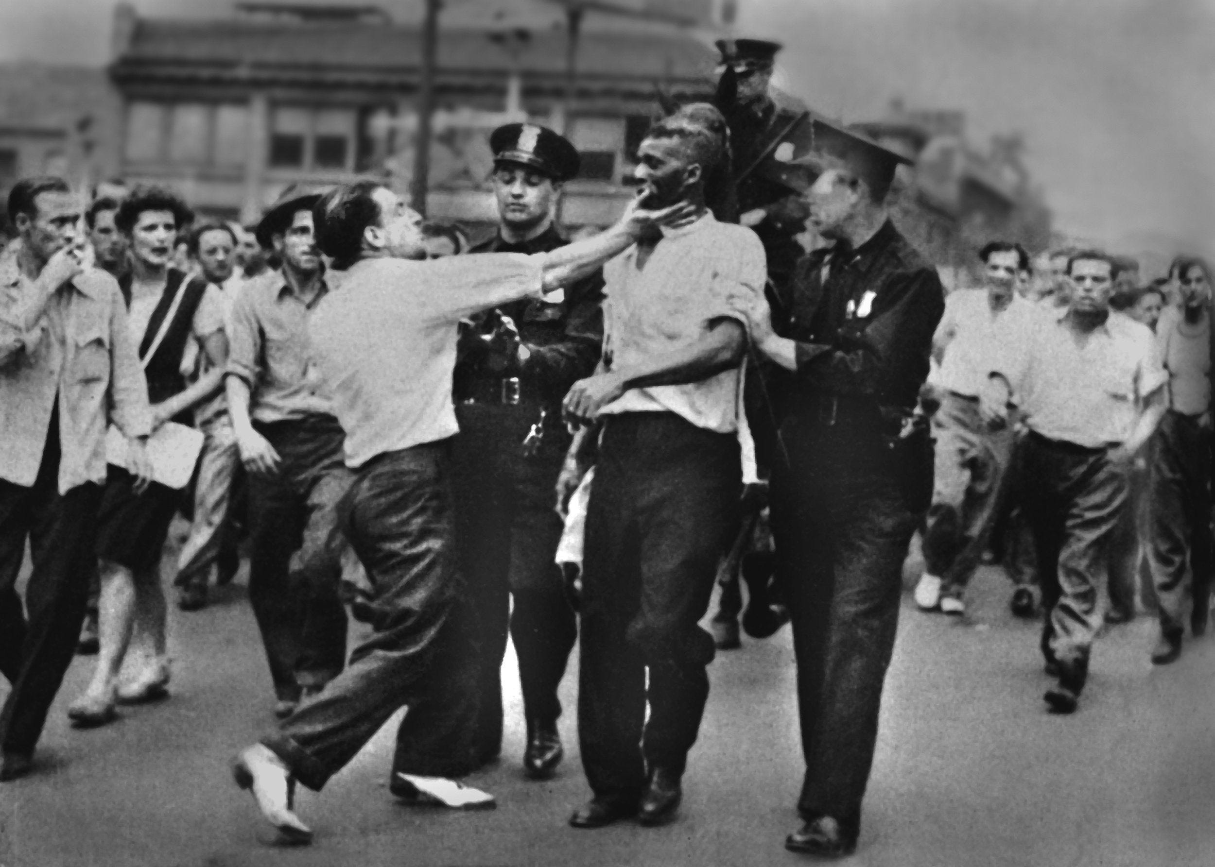 During the race riot of 1943 George Miller slaps Sam Mitchell while police lead the wounded man along Woodward Avenue. Free Press File Photo


