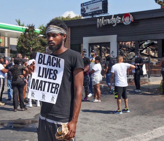 Kyna Sosa demonstrates Sunday, June 14, 2020, after protestors set fire to the Atlanta Wendy's where Rayshard Brooks, a 27-year-old Black man, was shot and killed by Atlanta police.