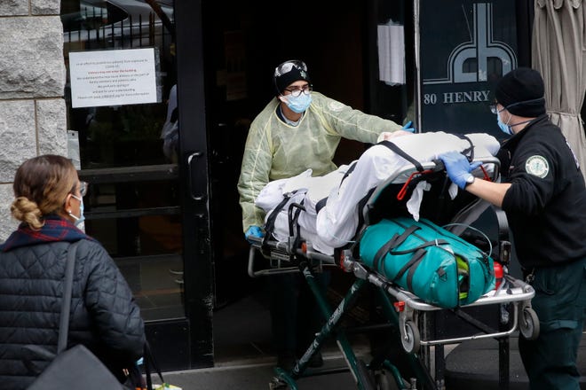 FILE- In this April 17, 2020, file photo, a patient is wheeled into Cobble Hill Health Center by emergency medical workers in the Brooklyn borough of New York. A grim blame game with partisan overtones is breaking out over COVID-19 deaths among nursing home residents, a tiny slice of the population that represents a shockingly high proportion of Americans who have perished in the pandemic. (AP Photo/John Minchillo, File)