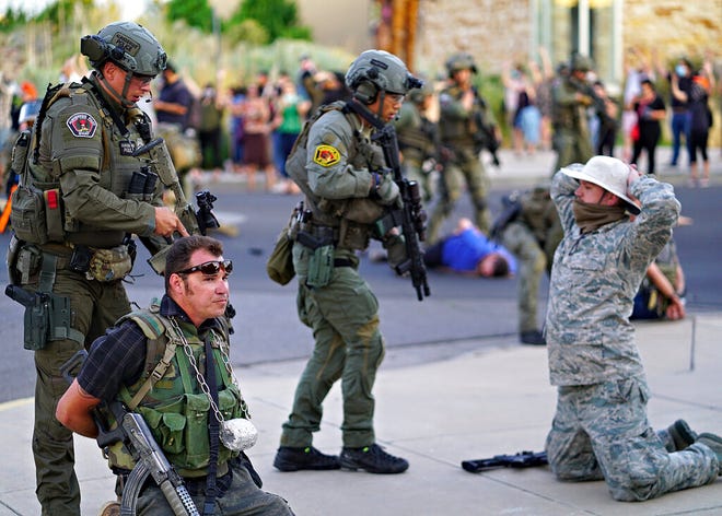 Albuquerque police detain members of the New Mexico Civil Guard, an armed civilian group, following the shooting of a man during a protest over a statue of Spanish conqueror Juan de Oñate on Monday, June 15, 2020, in Albuquerque.