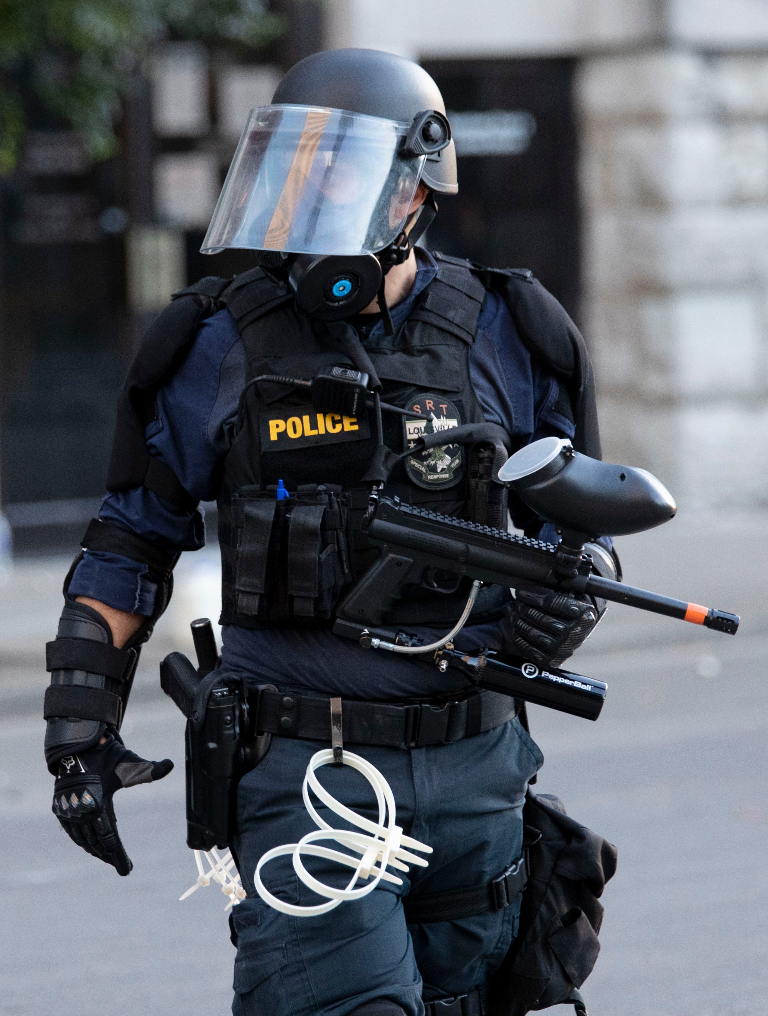 A police officer carries a pepper-spray ball gun Sunday, May 31, 2020, in downtown Louisville.