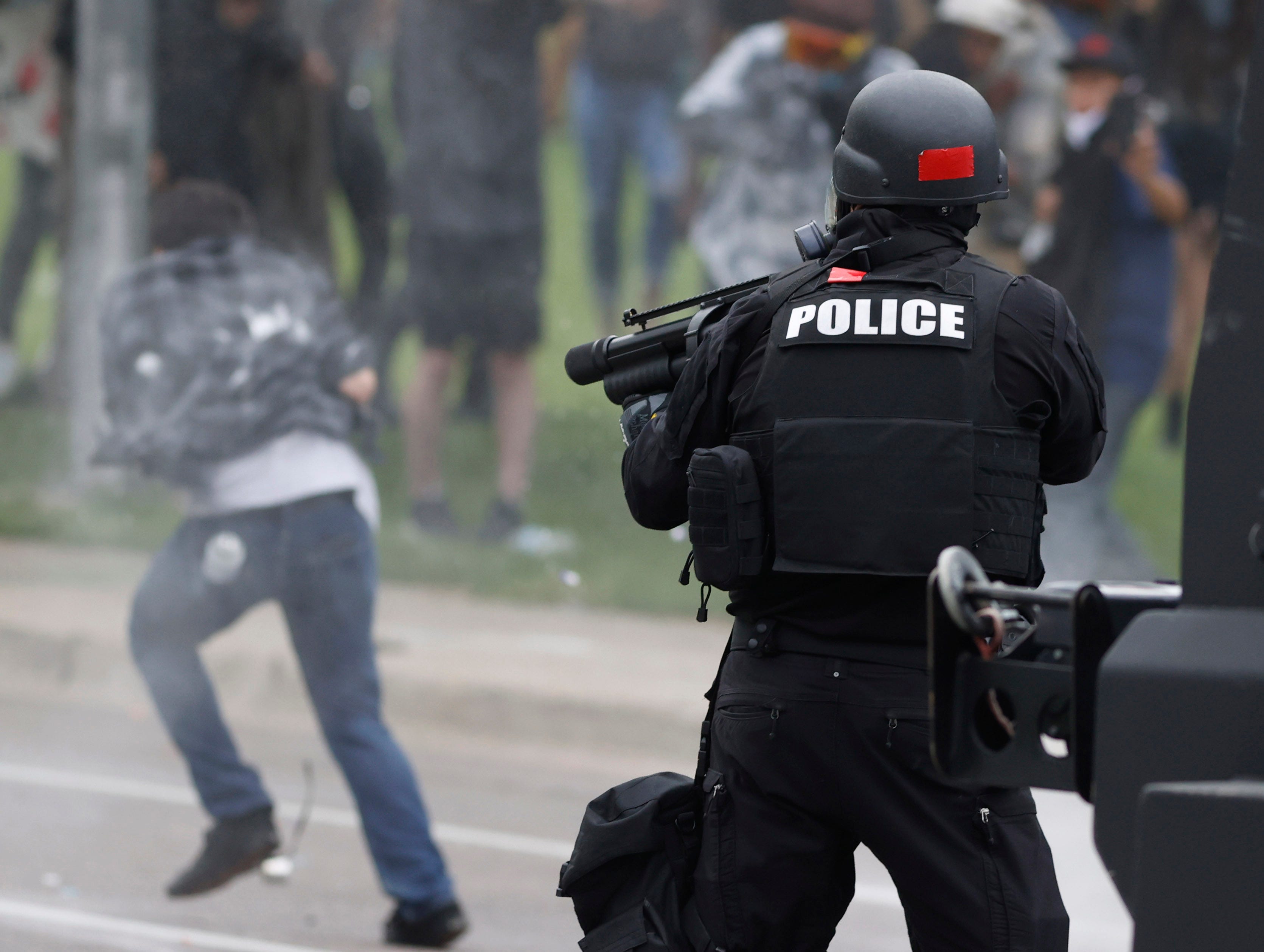 Denver police shoot a projectile at a man as he retreats during a protest outside the State Capitol over the death of George Floyd, Saturday, May 30, 2020, in Denver.