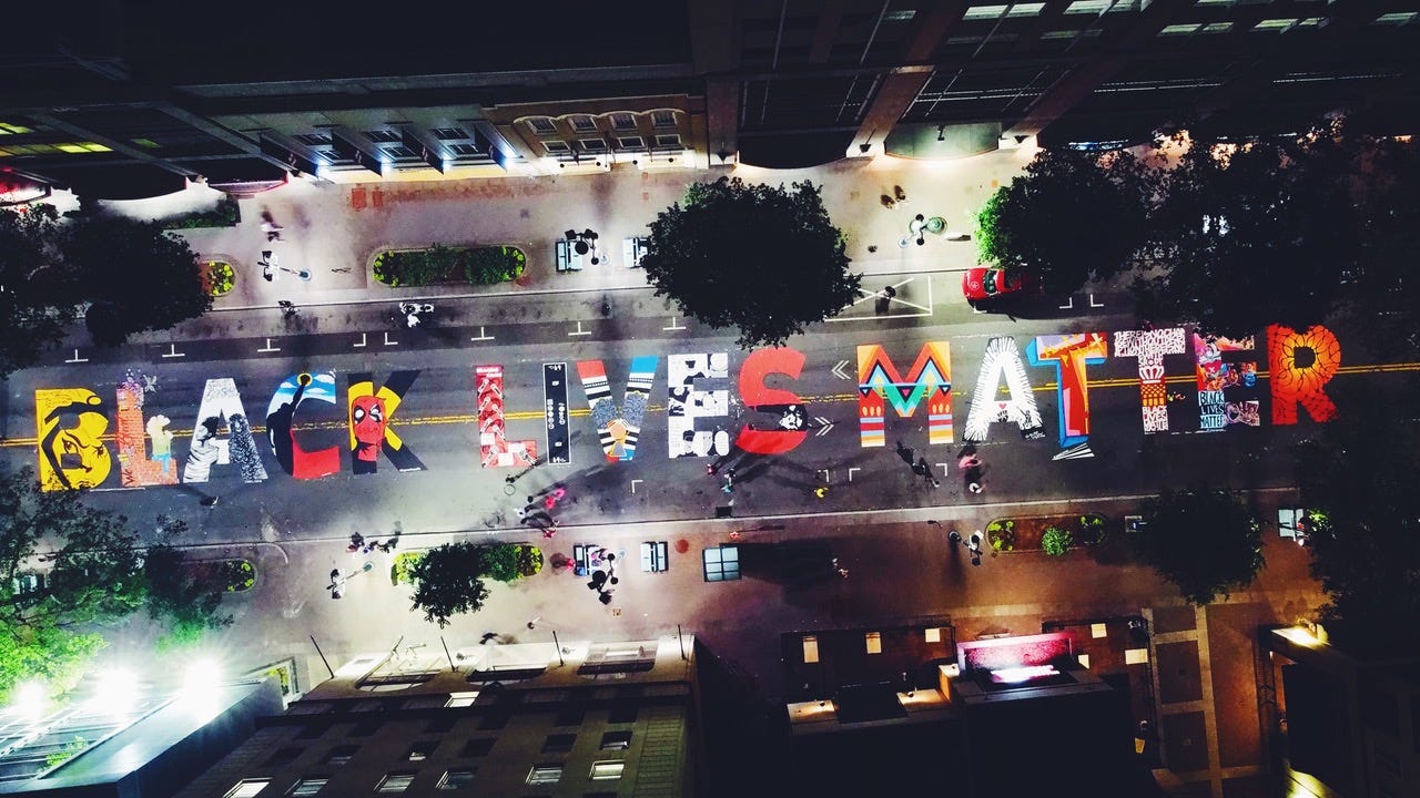 A BLACK LIVES MATTER mural lines a street in Charlotte. Artist Dakota Aiyanna painted the first letter L.