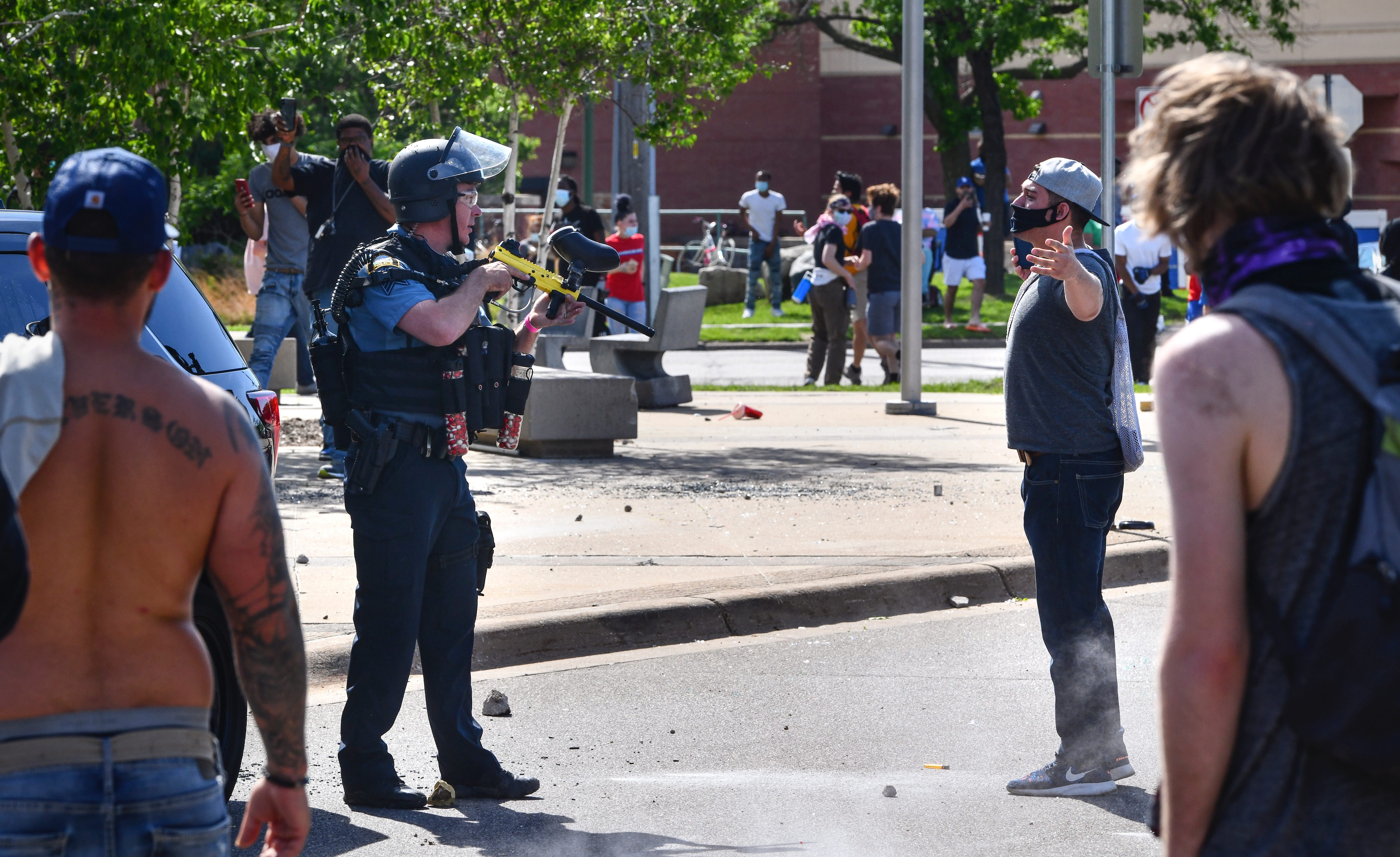 A St. Paul police officer armed with a less-lethal paintball-style weapon faces off with a protester in front of the Target store near the intersection of University Avenue West and Hamline Avenue North Thursday, May 28, 2020, in St. Paul, Minn.